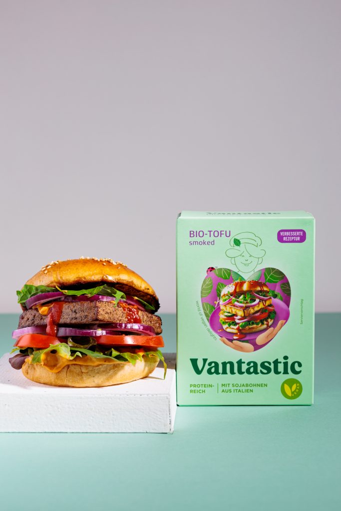 Minimalistisches Bild mit einem Tofuburger links und der Produktverpackung rechts.